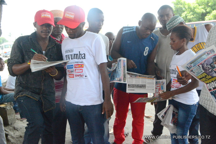 1.Sadick Muhidin (kushoto) akielekezwa na Ofisa Masoko wa Global,Yohana Mkanda (katikati) namna ya kujaza kuponi yake kushiriki Bahati nasibu ya Shinda Nyumba.
