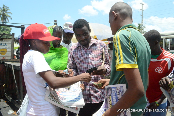 1.Wasomaji wa Stendi ya Daladala ya Chamazi wakichangamkia kununua magazeti kwa muuzaji wa Globa,(mwenye fulana nyeupe kushoto).