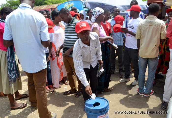 11.Wakazi wa Kiluvya wapewa zawadi zao za kofia kuotoka kwa Ofisa Masoko wa Global,wakati wakishirikia kujaza kuponi na kutumbukiza ndani ya ndoo maalum ili kushiriki Bahati nasibu.