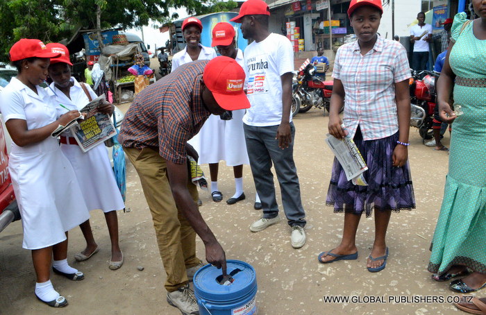 3.Mmoja wa wasomaji wa Gazeti la Uwazi akiingia Kuponi yake katika ndoo maalumu ya kushiriki Bahati nasibu hiyo.