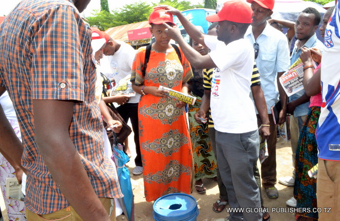 5.Ofisa Masoko wa Golabl,Yohana Mkanda (mwenye fulana nyeupe kulia) akimvisha kofia msomaji wa Gazeti la Uwazi baada ya kukata kuponi yake na kushiriki Bahati nasibu hiyo.