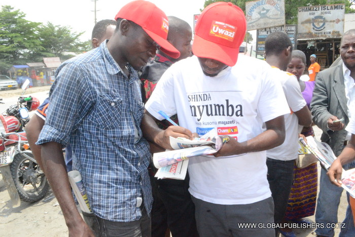 7.Mkanda (kulia) akimsaidia mmoja wa washiriki wa Bahati nasibu ya Shinda Nyumba kumjazia kuponi yake.