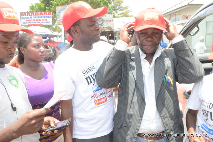 9.Mshiriki wa Shinda Nyumba,Said Bia (kulia) akivalishwa kofia na Ofisa Masoko wa Global baada ya zoezi la kujaza kuponi yake na kushiriki.