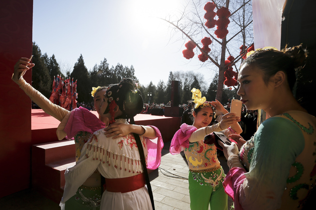 Chinese dancers dressed in traditional costume take selfies in backstage during a temple fair for a Lunar New Year celebration in Beijing, Monday, Feb. 8, 2016. Millions of Chinese began celebrating the Lunar New Year, which marks the Year of Monkey on the Chinese zodiac. (AP Photo/Andy Wong)