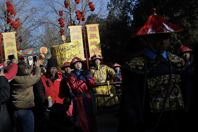 Qi Xueen, a performer dressed as a Qing Dynasty emperor, seated on a sedan chair, center, is carried during the ancient Qing Dynasty ceremony in which emperors prayed for good harvest and fortune at a temple fair in Ditan Park during the first day of the Chinese Lunar New Year in Beijing, Monday, Feb. 8, 2016. Millions of Chinese began celebrating the Lunar New Year, which marks the Year of the Monkey on the Chinese zodiac. (AP Photo/Andy Wong)