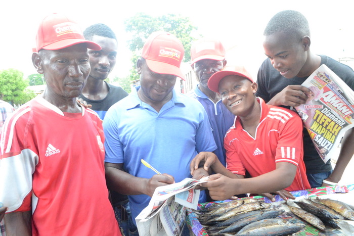 1.Muuzaji maarufu wa samaki katika soko la Mlandizi,Soud Kigola(wapili kushoto) akijaza kuponi yake huku wasomaji wengine wa Gazeti la Amani wakimshuhudia.