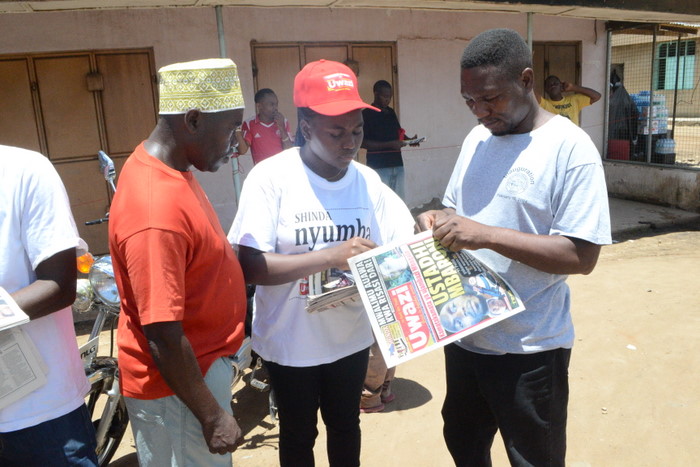 13.Wasomaji wa Gazeti la AMani wakinunua magazeti kwa muuzaji wa Global (katikati) ili kushiriki bahati nasibu hioyo.