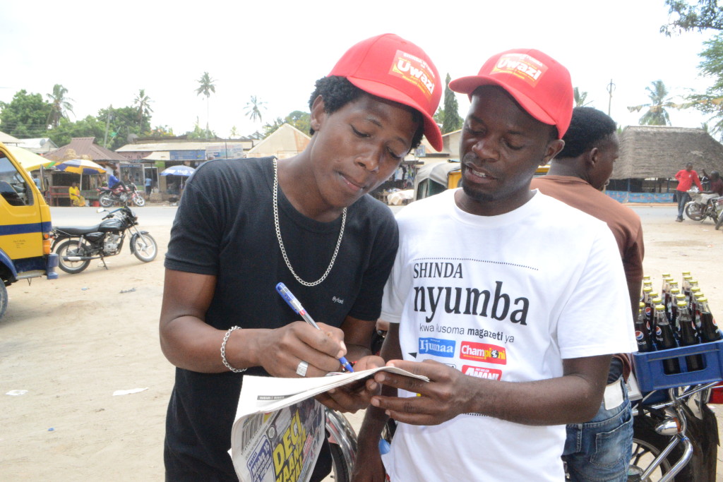 6.Kevin Aloyce Mkazi wa eneo la stendi ya daladala ya Goba akijaza kuponi yake ili kushiriki droo ya Shinda Nyumba.