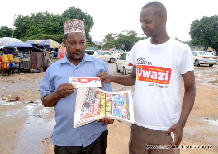 13.Muuzaji wa Gazeti la Uwazi eneo la Ubungo Stendi ya Mabasi,Halifa Rajab Nanga (kushoto) akipokea zawadi yake ya kuponi maalum kutoka kwa Ofisa Usambazaji,Jimmy Haroub.