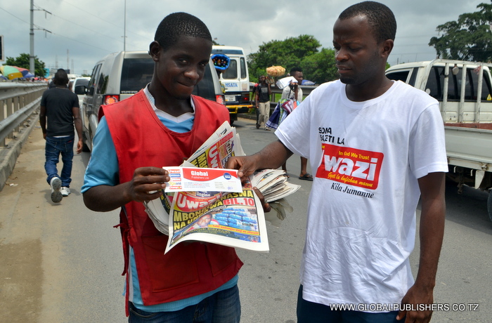 7.Ofisa Masoko wa Global,Yohana Mkanda (kulia) akimkabidhi muuzaji wa magazeti barabarani kuponi maalum ya zawadi baada ya kukutwa ameweka gazeti la Uwazi juu ya mengine.