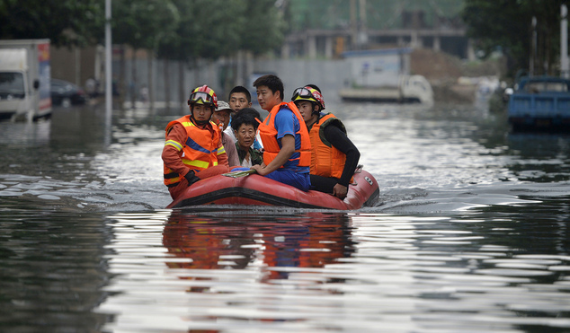 In this Thursday, July 21, 2016, photo, rescuers use a raft to transport people along a flooded street in Shenyang in northeastern China's Liaoning Province. Dozens of people have been killed and dozens more are missing across China after a round of torrential rains swept through the country earlier this week, flooding streams, triggering landslides and destroying houses. (Chinatopix Via AP)